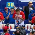 NEW YORK, NEW YORK - JULY 04: Defending champion Joey Chestnut (C) competes in the 2023 Nathan's Famous Fourth of July International Hot Dog Eating Contest on July 4, 2023 at Coney Island in the Brooklyn borough of New York City. The men's contest was postponed due to thunderstorms but later happened without spectators allowed into the